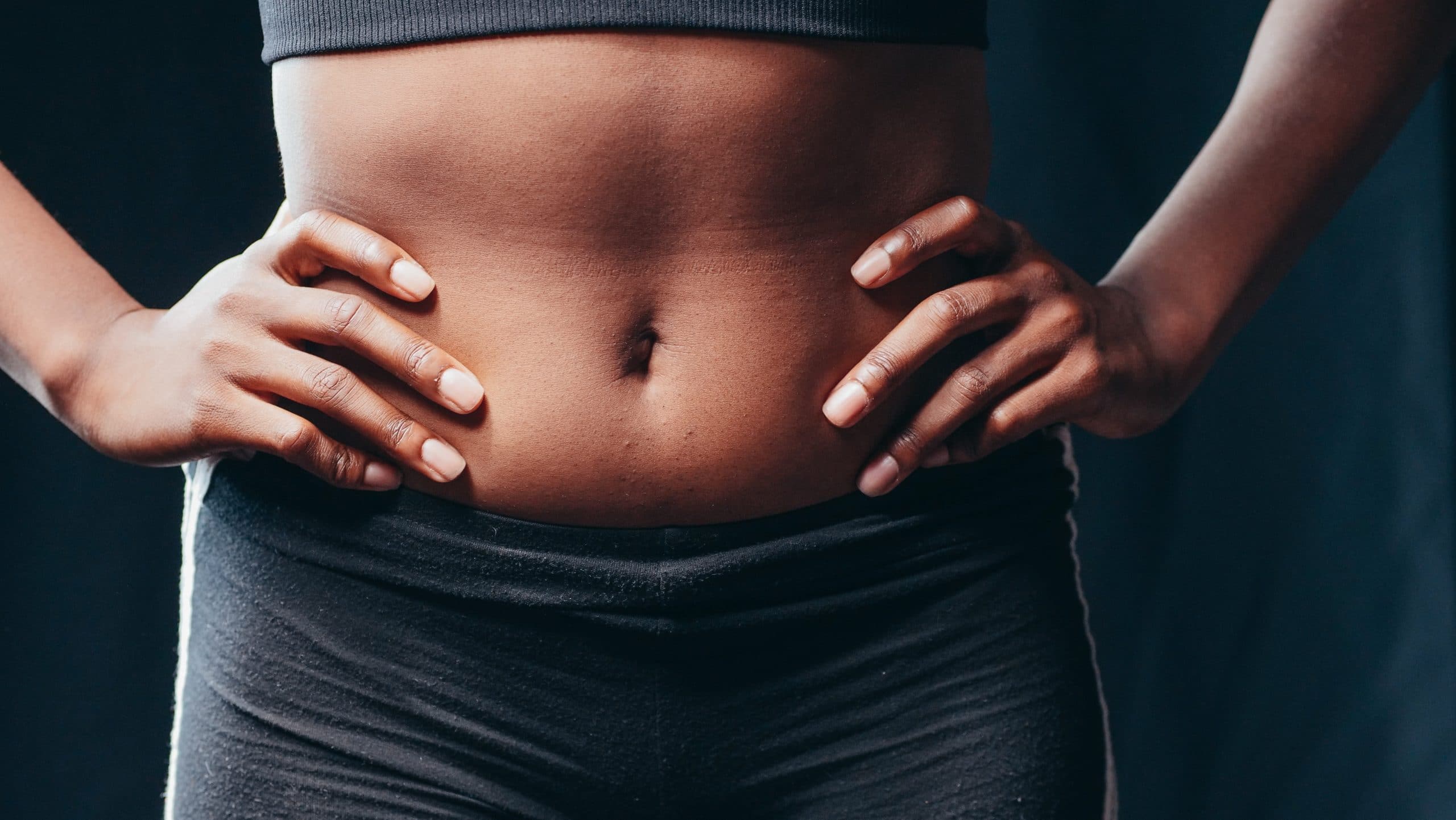 A Fit Woman’s Abdomen, Her Hands On Her Hips, After Receiving Liposuction And Fat Transfer.